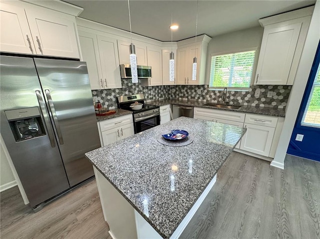 kitchen with light wood finished floors, white cabinets, a sink, and appliances with stainless steel finishes