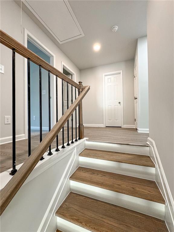 stairway featuring attic access and baseboards