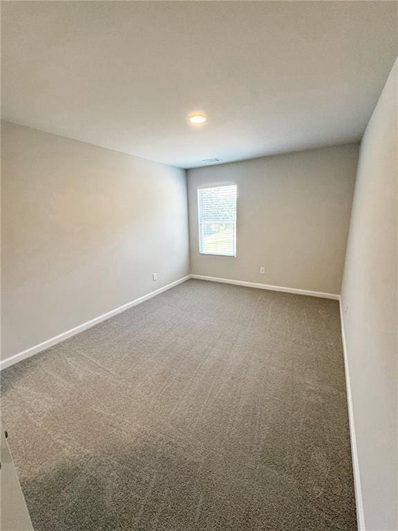 unfurnished room with baseboards and dark colored carpet