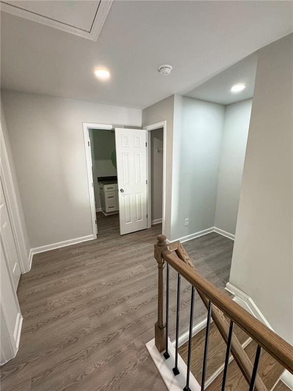 hallway with an upstairs landing, baseboards, and wood finished floors