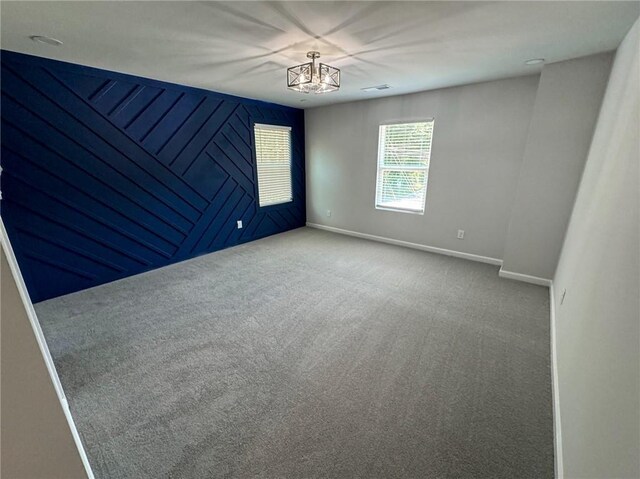 empty room with a chandelier, carpet floors, and baseboards