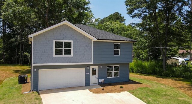 view of front facade with concrete driveway, an attached garage, cooling unit, and a front lawn