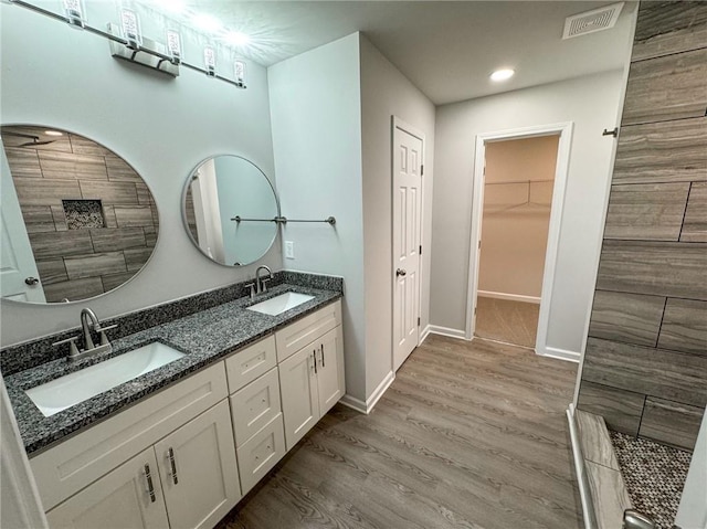 bathroom featuring wood finished floors, visible vents, a sink, and double vanity