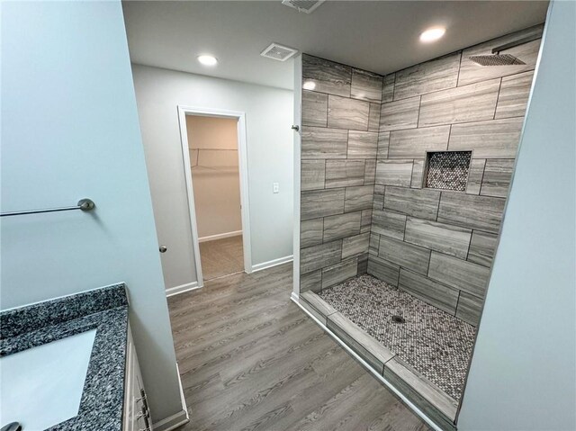 bathroom featuring a tile shower, wood finished floors, visible vents, and recessed lighting
