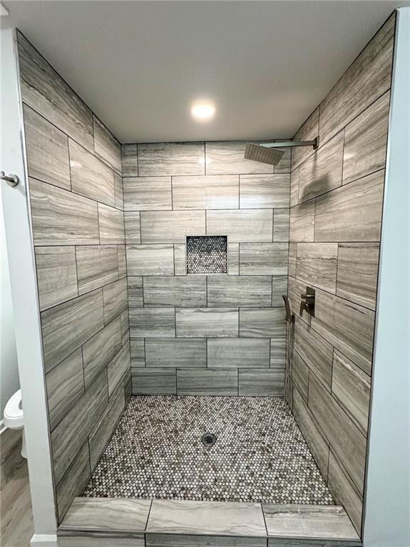 bathroom featuring toilet and tiled shower