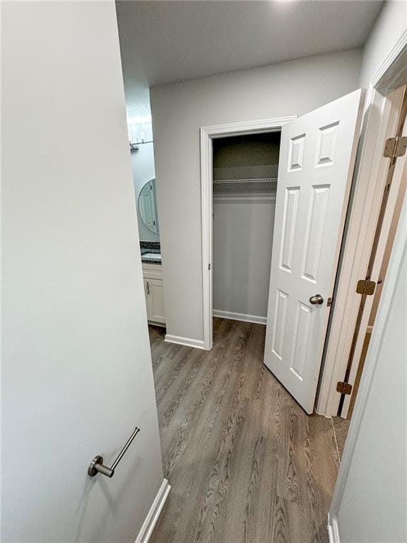 corridor featuring baseboards and wood finished floors