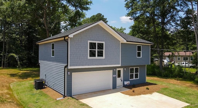 view of front of house with a front lawn, driveway, cooling unit, and an attached garage