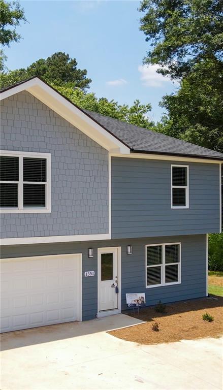 view of front of home with driveway, a shingled roof, and a garage