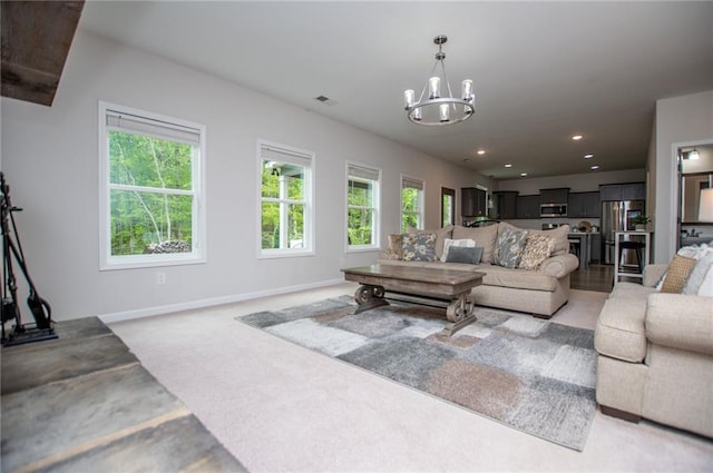 living area with baseboards, plenty of natural light, recessed lighting, and a notable chandelier