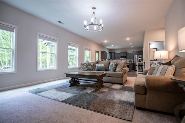 living area featuring light colored carpet, baseboards, an inviting chandelier, and visible vents