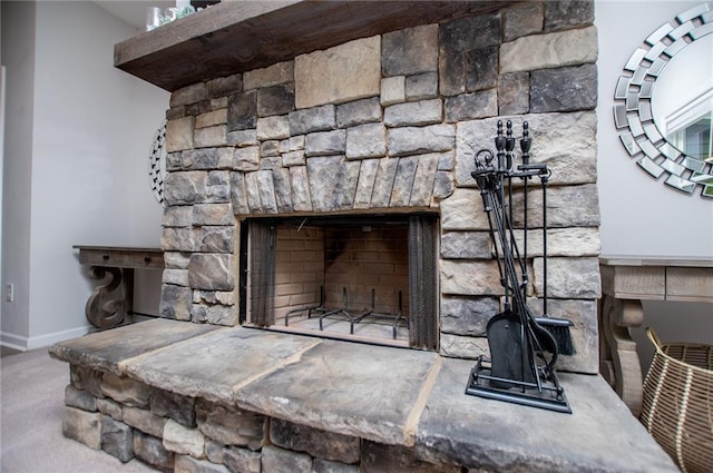 room details with a stone fireplace, carpet flooring, and baseboards