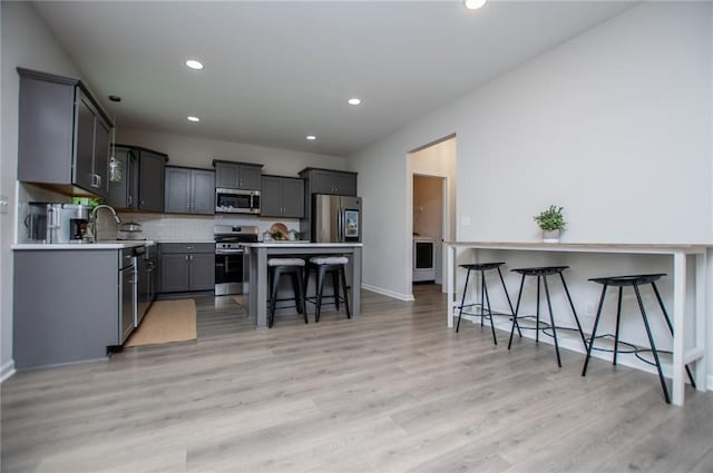 kitchen with recessed lighting, a breakfast bar, stainless steel appliances, and light wood finished floors