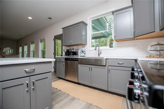 kitchen featuring visible vents, light wood-style floors, tasteful backsplash, stainless steel dishwasher, and gray cabinetry