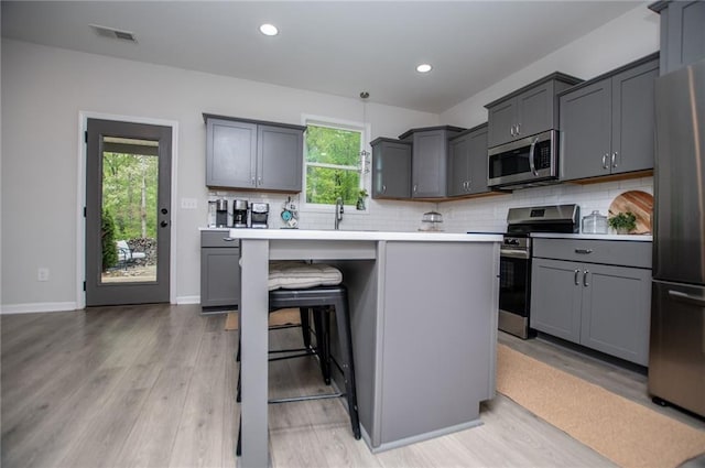 kitchen featuring visible vents, light wood-style flooring, appliances with stainless steel finishes, and tasteful backsplash