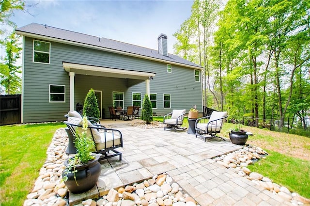 rear view of house featuring a fenced backyard, a chimney, a yard, and a patio area