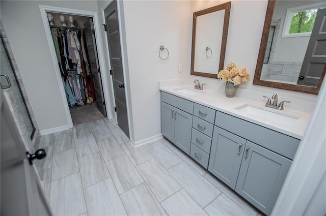 bathroom featuring double vanity, baseboards, a spacious closet, and a sink