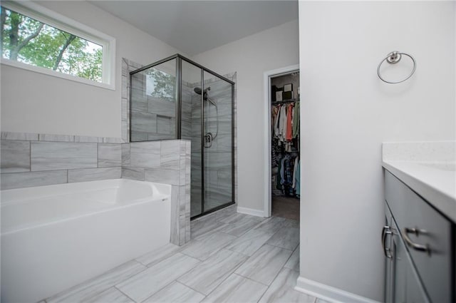 full bath featuring a spacious closet, a shower stall, a garden tub, and vanity