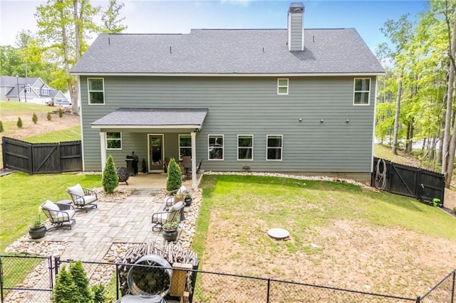 rear view of house featuring a fenced backyard, a chimney, a gate, a patio area, and a yard