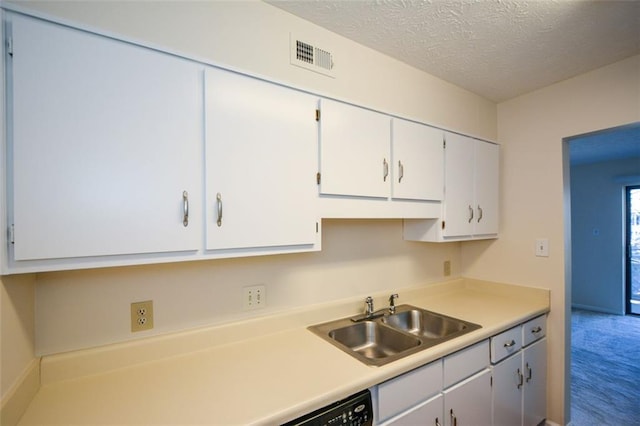 kitchen with carpet flooring, a textured ceiling, white cabinetry, and sink