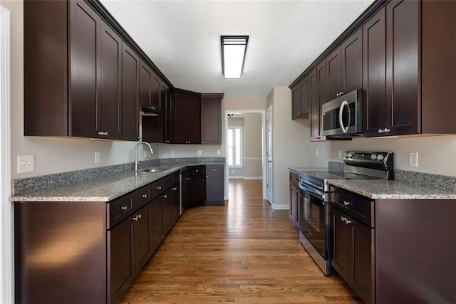 kitchen with appliances with stainless steel finishes, dark brown cabinets, and a sink