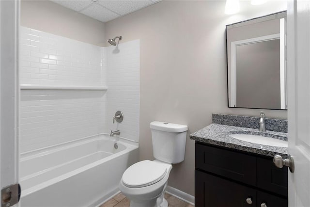 bathroom with a paneled ceiling, toilet, vanity, baseboards, and shower / washtub combination