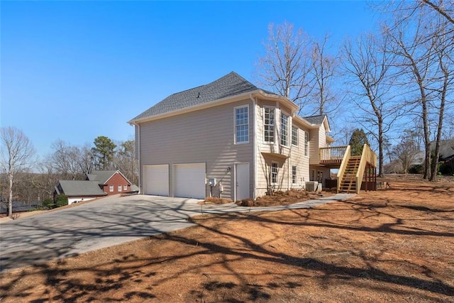 view of side of property with a deck, a garage, central AC, driveway, and stairway