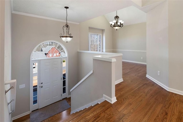 entrance foyer with lofted ceiling, baseboards, a chandelier, and wood finished floors