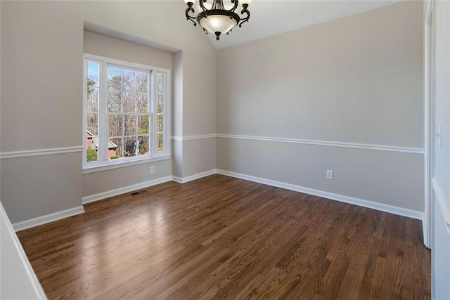 unfurnished room featuring baseboards, dark wood-type flooring, visible vents, and an inviting chandelier