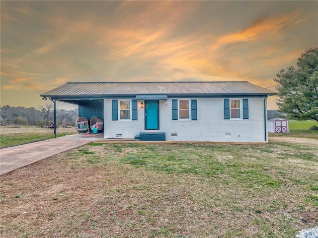 view of front of home with crawl space, an attached carport, metal roof, and a lawn