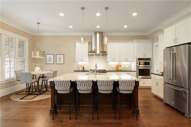 385 Windy Pines Trl, Roswell, GA 30075 - kitchen featuring appliances with stainless steel finishes, wall chimney exhaust hood, a breakfast bar area, a center island with sink, and recessed lighting