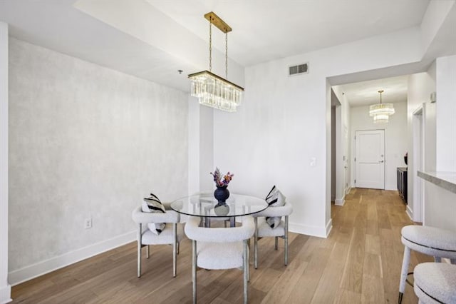 dining space featuring light hardwood / wood-style floors and a notable chandelier