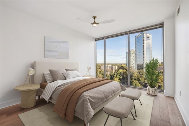 bedroom with ceiling fan, a wall of windows, and light hardwood / wood-style floors