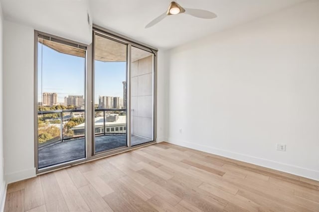 unfurnished room with floor to ceiling windows, ceiling fan, light hardwood / wood-style flooring, and a healthy amount of sunlight