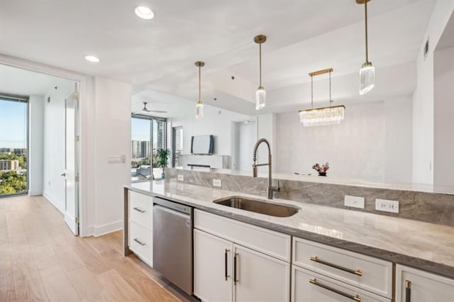 kitchen featuring sink, dishwasher, light stone counters, and white cabinetry