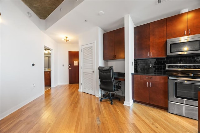400 W Peachtree St NW Unit 3614, Atlanta, GA 30308 - kitchen with light wood-style flooring, appliances with stainless steel finishes, dark countertops, backsplash, and baseboards