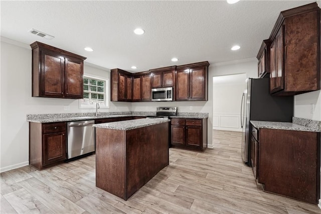 56 Sugar Leaf Ln, Jefferson, GA 30549 - kitchen featuring stainless steel appliances, ornamental molding, dark brown cabinets, light wood-style floors, and a center island