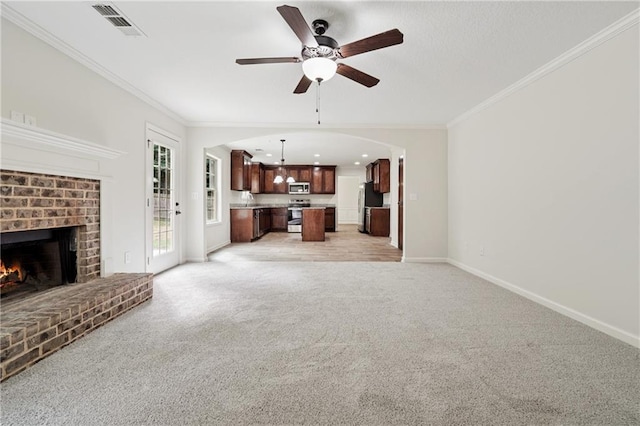 56 Sugar Leaf Ln, Jefferson, GA 30549 - unfurnished living room featuring a ceiling fan, crown molding, light colored carpet, a brick fireplace, and arched walkways