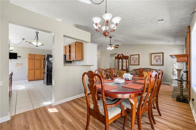 dining room featuring vaulted ceiling, a textured ceiling, ceiling fan with notable chandelier, and light wood-style floors