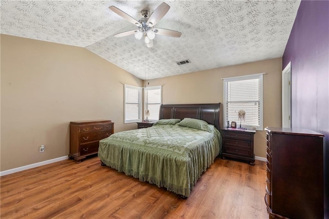 bedroom with visible vents, vaulted ceiling, baseboards, and wood finished floors