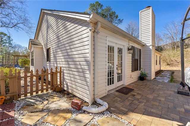 view of property exterior featuring a chimney, french doors, and a patio