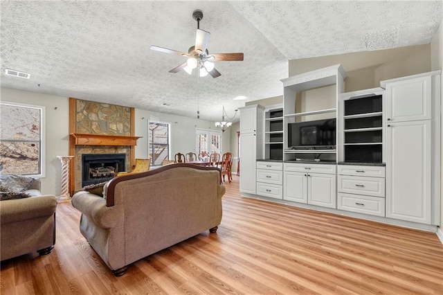 living area with visible vents, a fireplace, a textured ceiling, and light wood finished floors