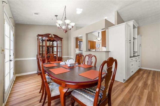 dining area with light wood-style floors, vaulted ceiling, a notable chandelier, and baseboards