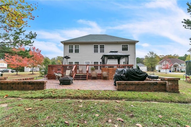 rear view of house featuring a yard, an outdoor fire pit, a wooden deck, a gazebo, and a patio area