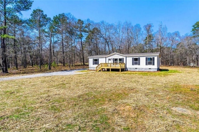 manufactured / mobile home featuring crawl space, a wooden deck, a front lawn, and a view of trees