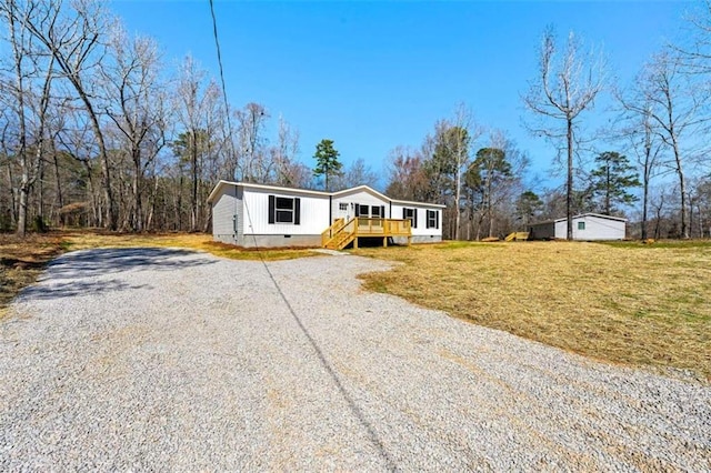 manufactured / mobile home with a front lawn, crawl space, a deck, and gravel driveway