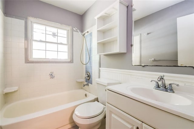 bathroom featuring vanity, toilet, shower / bathtub combination, and a wainscoted wall
