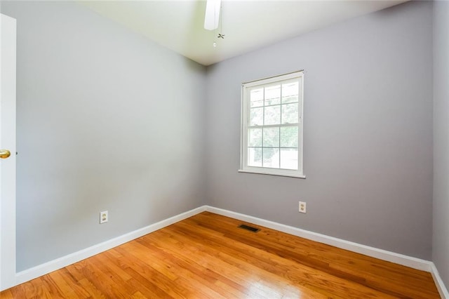 spare room with baseboards, light wood finished floors, and ceiling fan