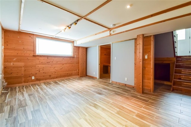 empty room featuring wood walls, wood finished floors, and healthy amount of natural light