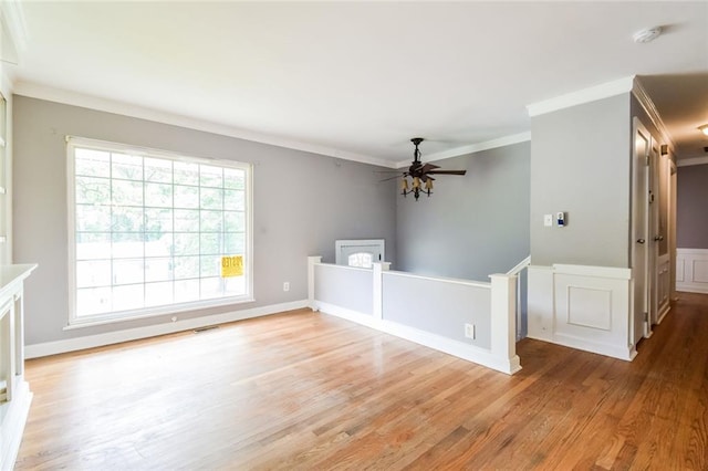 unfurnished living room featuring light wood-style floors, crown molding, and a ceiling fan