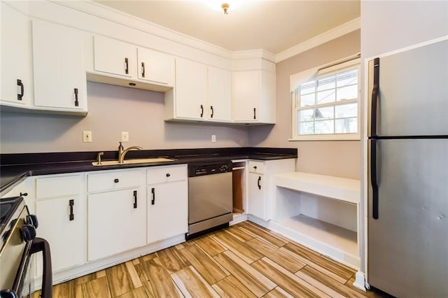 kitchen featuring appliances with stainless steel finishes, a sink, white cabinetry, dark countertops, and light wood finished floors